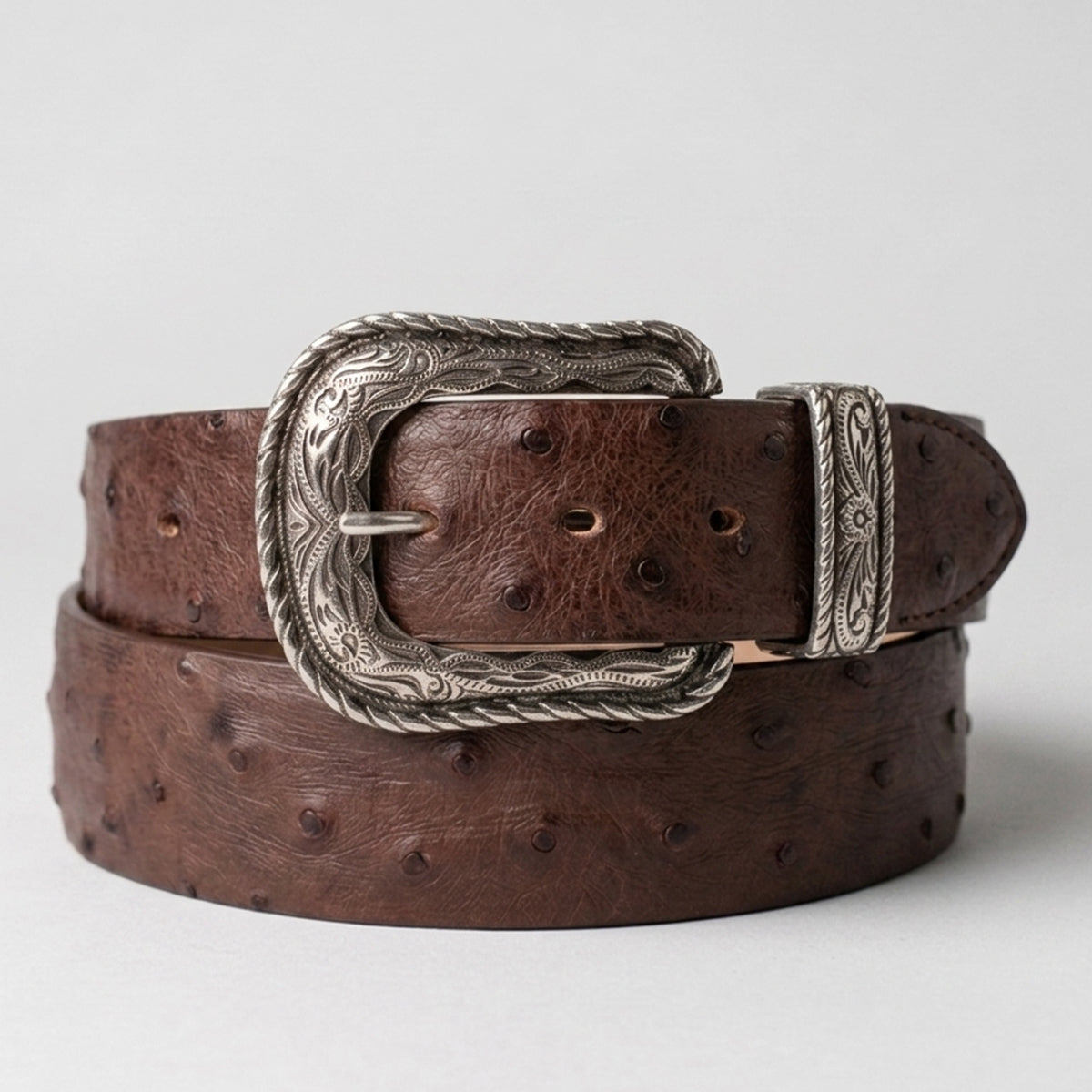 Los Altos men's tobacco brown ostrich leather belt with a silver-toned western heel-bar buckle, coiled on a light gray background.