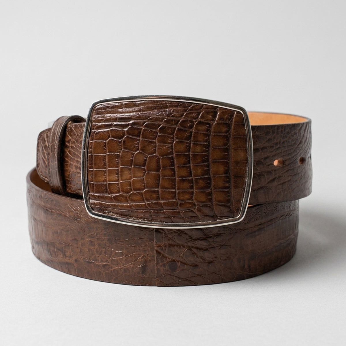 Los Altos men's brown caiman belly leather western belt with a silver-tone metal buckle, coiled on a light gray background.
