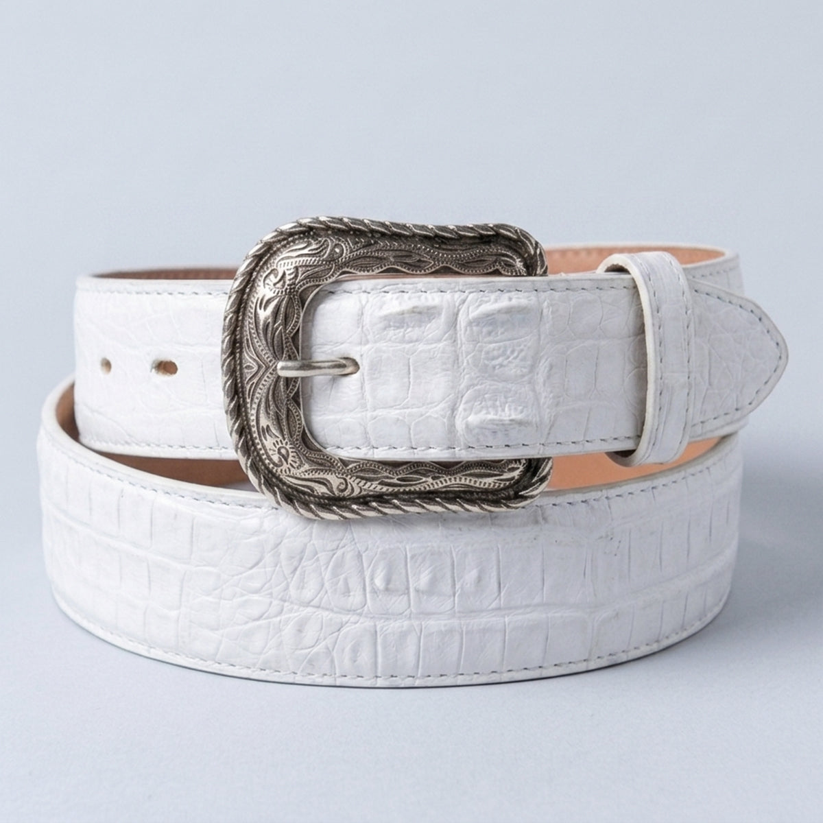 Los Altos white caiman hornback leather belt with silver-toned western-style buckle, coiled on a light gray background.