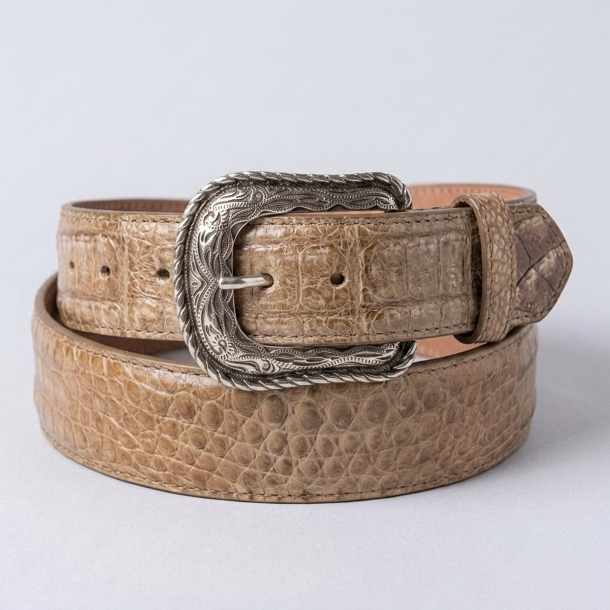 Los Altos men's Sahara Stone genuine caiman belly leather belt showing a rugged sandy-taupe scale texture with an engraved silver western heel-bar buckle.