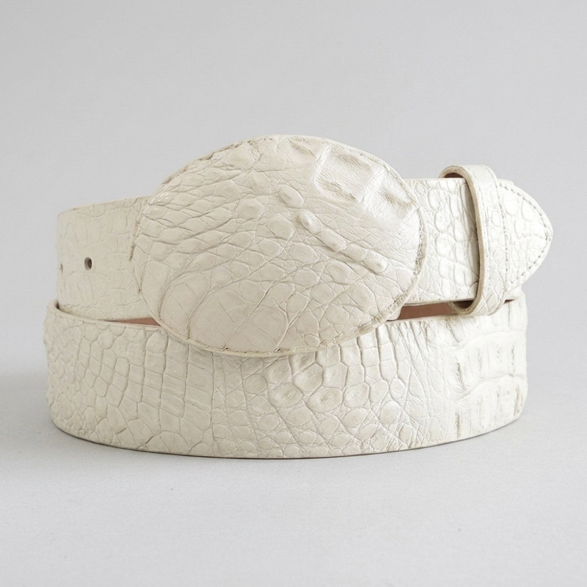 Los altos off-white crocodile leather belt with a large oval buckle, coiled on a light gray background.