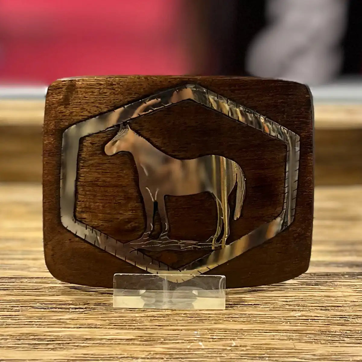 Handcrafted mesquite wood Western belt buckle with a polished stainless steel horse inlay framed inside a geometric border.