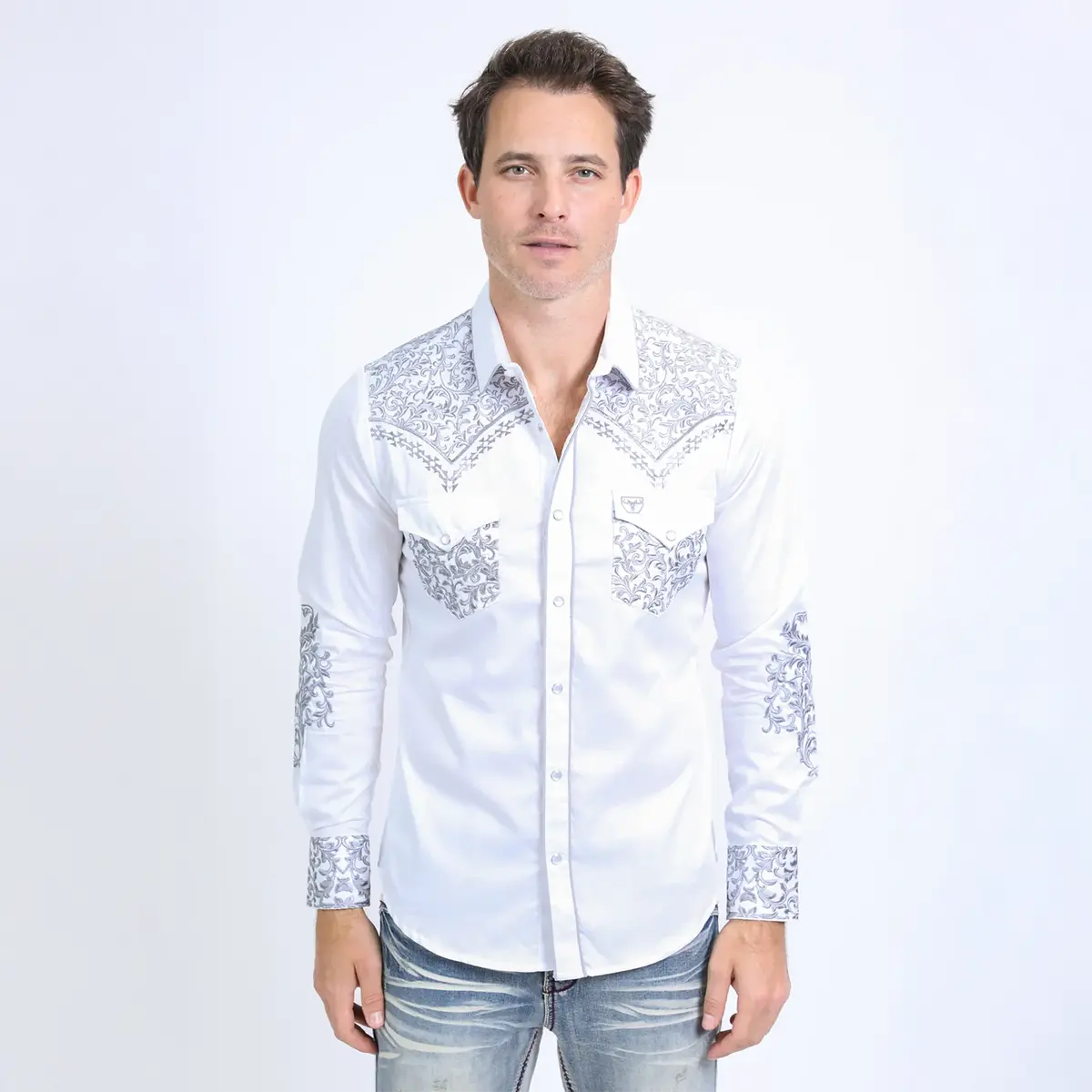 Straight-on studio view of a male model wearing the Platini men's white tapestry embroidered long sleeve shirt with jeans.