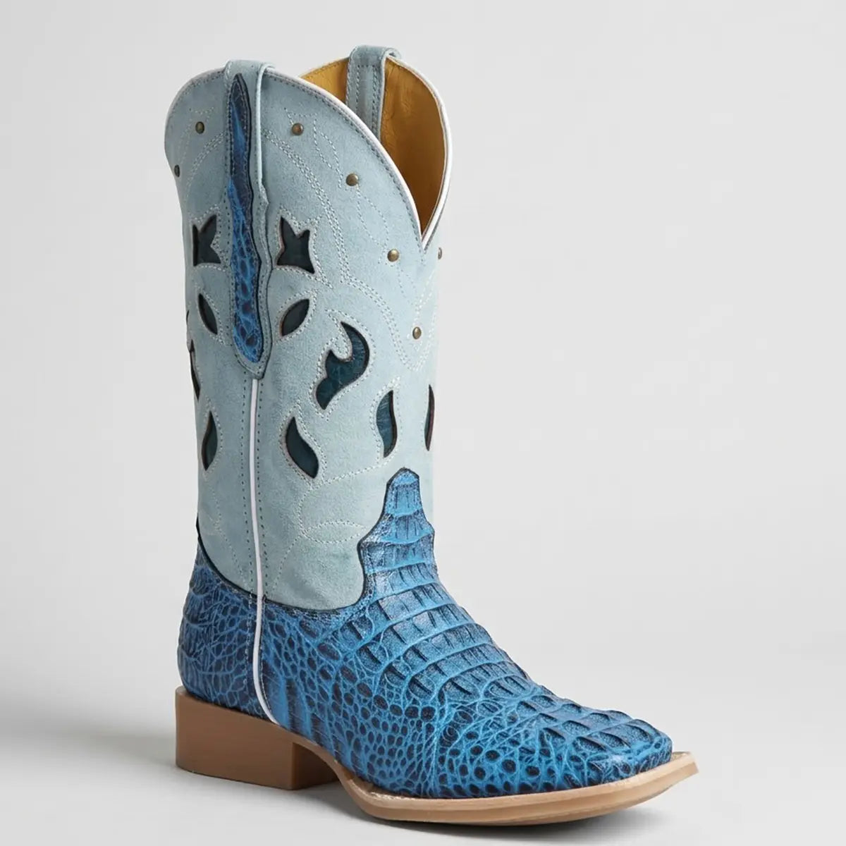 Studio profile view of the El General Women's Western boot showcasing the vibrant royal blue caiman hornback print foot, light blue suede cutout shaft, brass studs, and square toe.