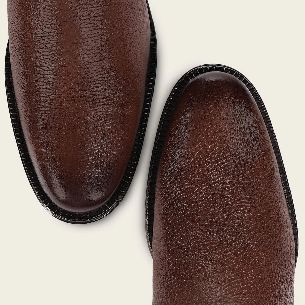 Close up of Cuadra brown leather shoe toe's on a light beige background.
