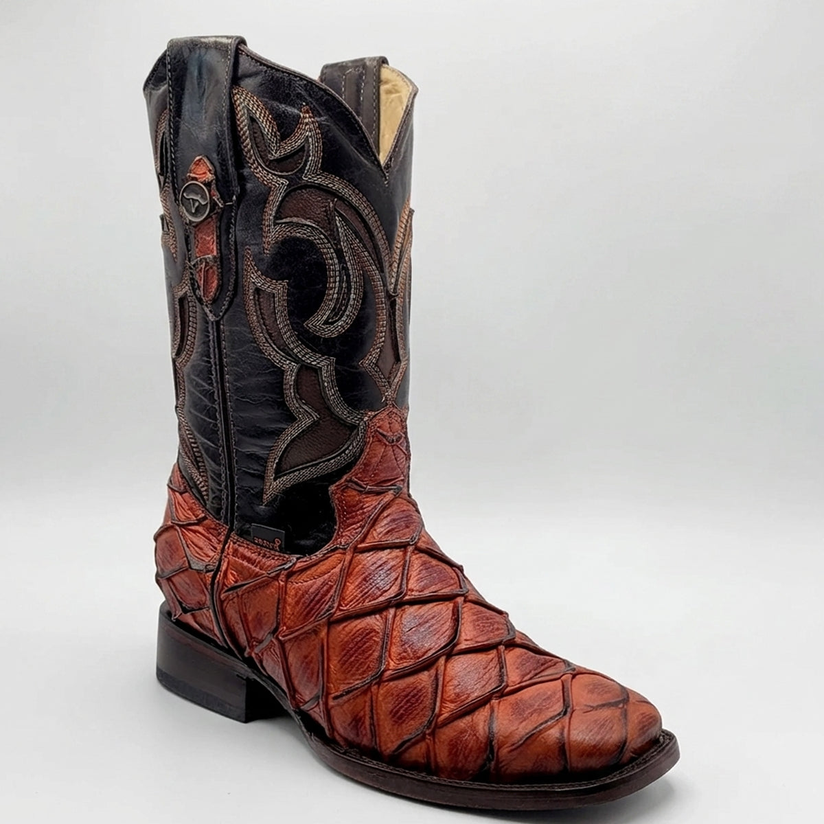 Hooch men's western cowboy boot featuring a cognac brown textured pirarucu fish scale print vamp, a dark brown leather shaft with embroidery, and a square toe.