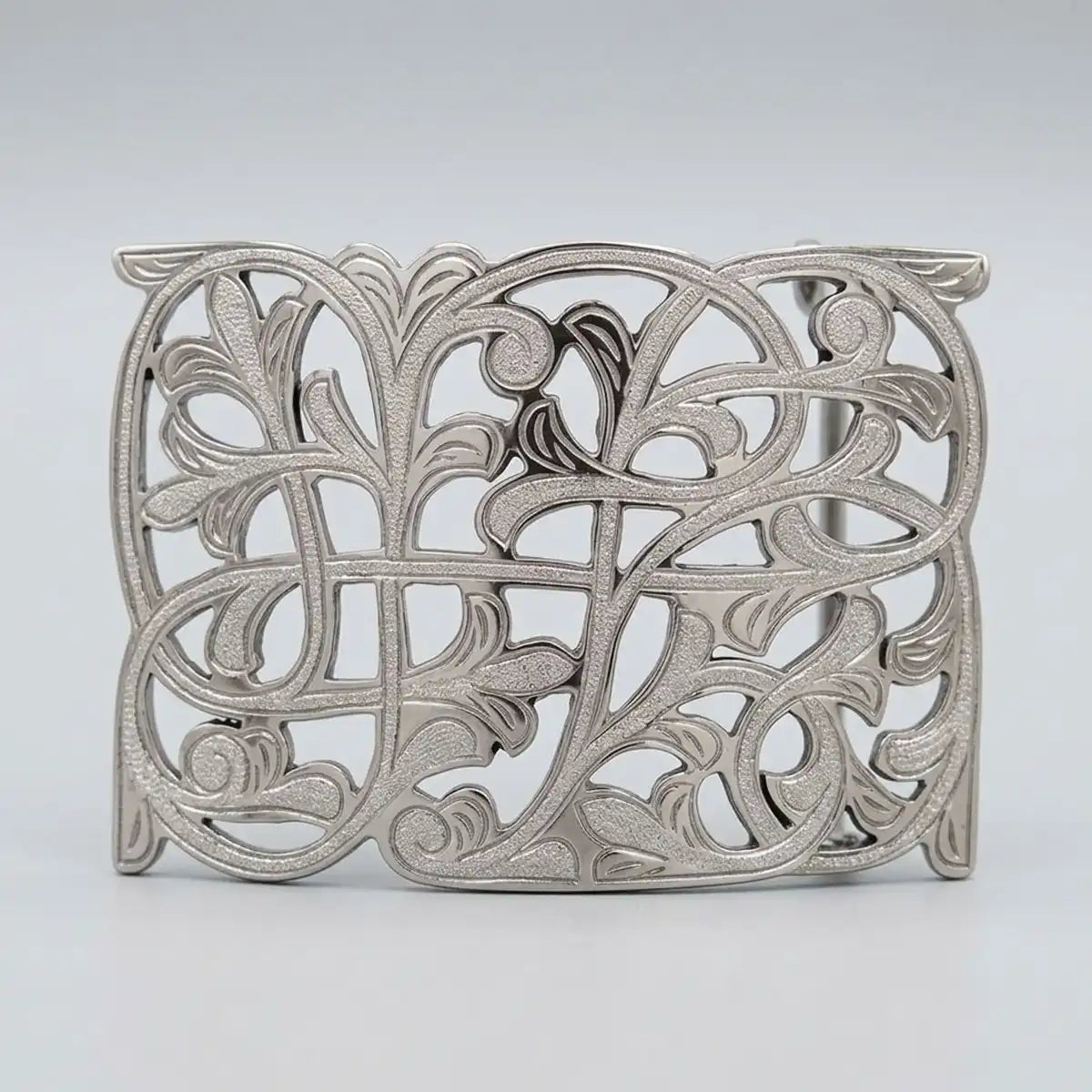 An ornate silver filigree western belt buckle with intricate leaf and scrollwork patterns, shown on a neutral light gray background.