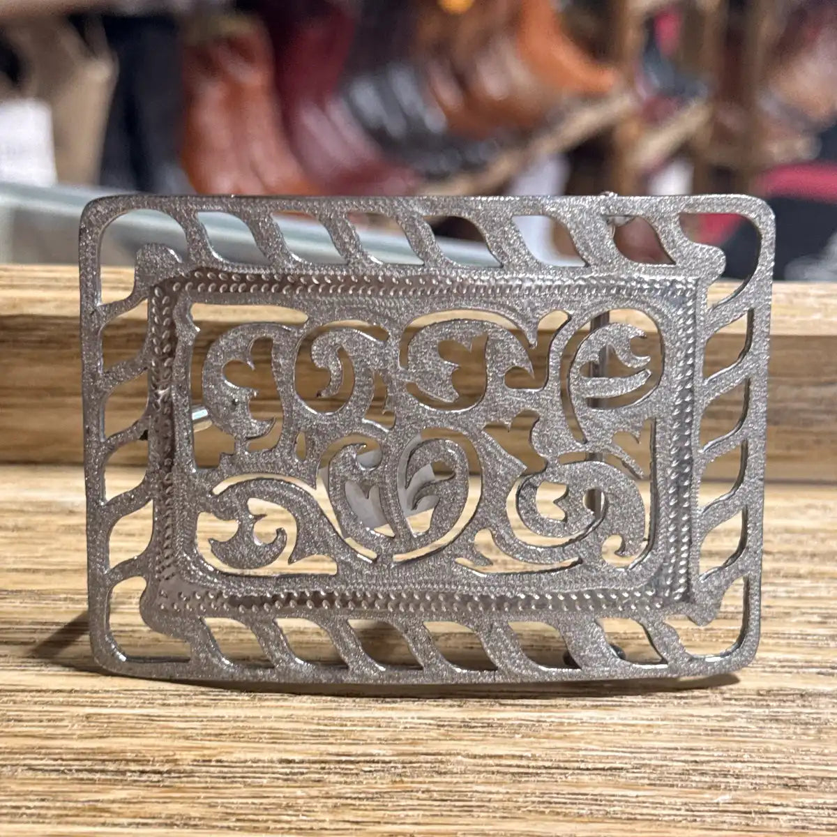 Stainless steel cutout Western belt buckle featuring intricate floral filigree scrollwork framed by a rope pattern outer border.