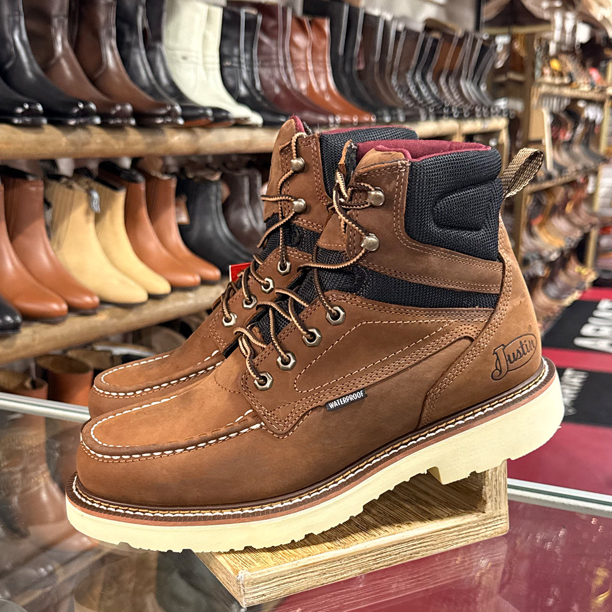 Justin brown leather work boot with visible brand logo on a wooden stand.