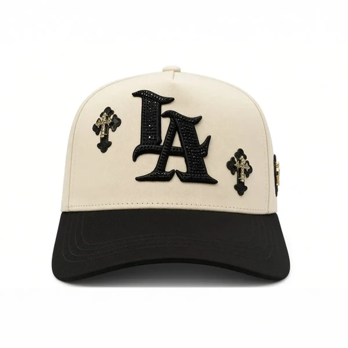 Front studio view of the LA Chrome beige and black cap displaying the rhinestone LA logo and gold cross appliques.