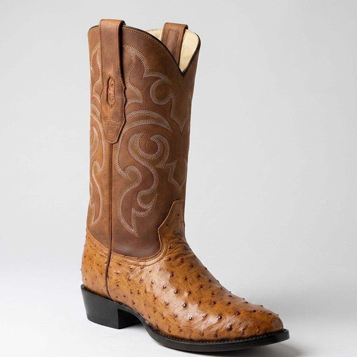 Los Altos men's amber tan ostrich leather round toe cowboy boot featuring white western embroidery on the shaft and a black block heel, shown against a light gray background.