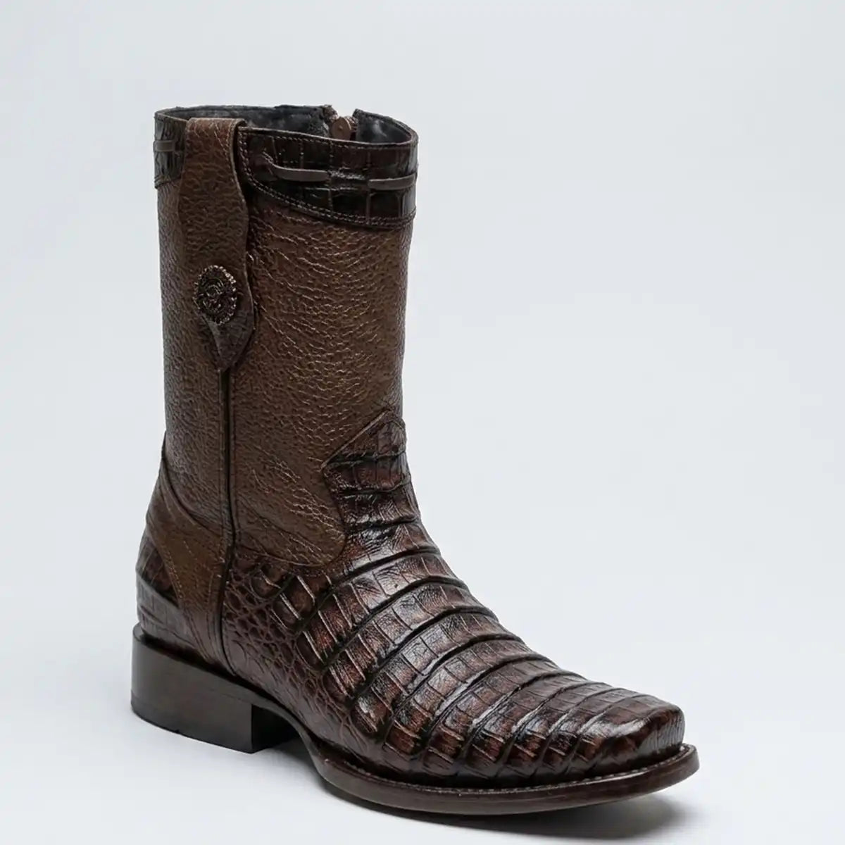 A dark brown western boot featuring textured leather and crocodile skin embossed panels, a pointed square toe, and a low stacked heel, shown against a light gray background.