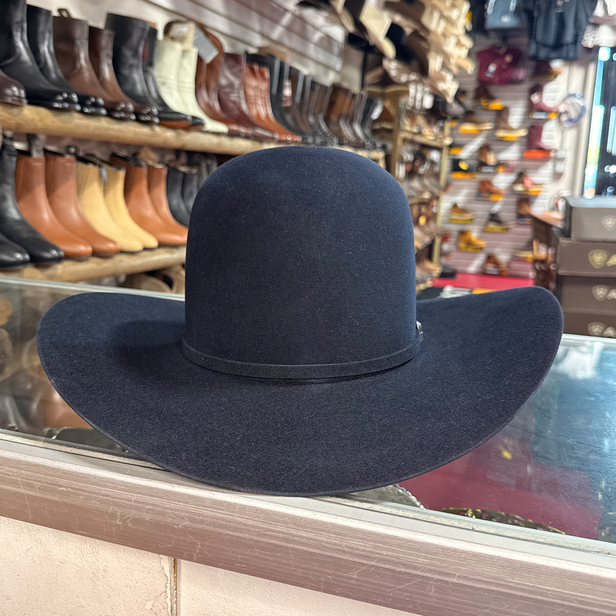 American Hat Company navy blue wide-brimmed felt western hat on a glass surface.