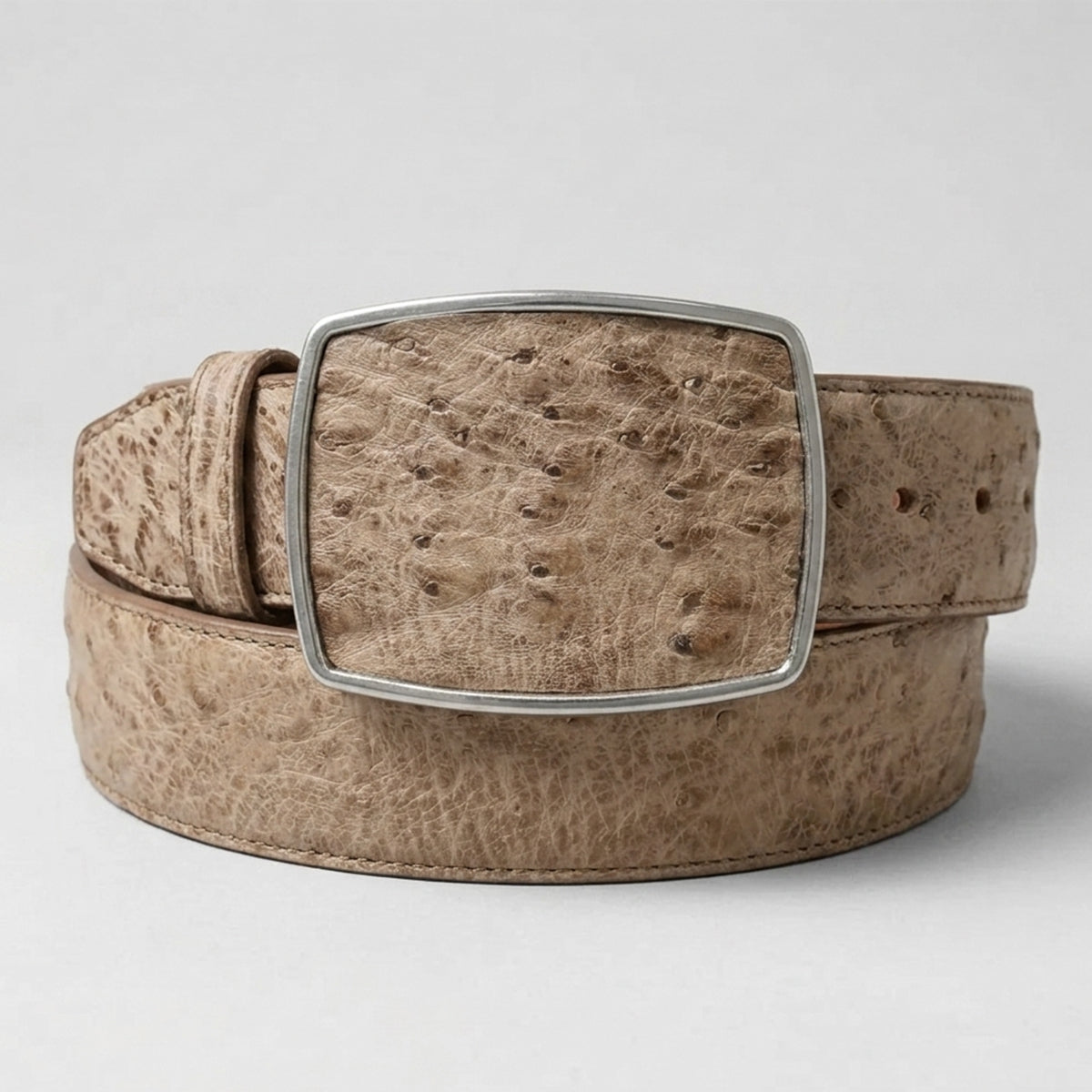 Los Altos men's ostrich belly leather belt in a light tan color with a silver-tone rectangular buckle, coiled on a light gray background.
