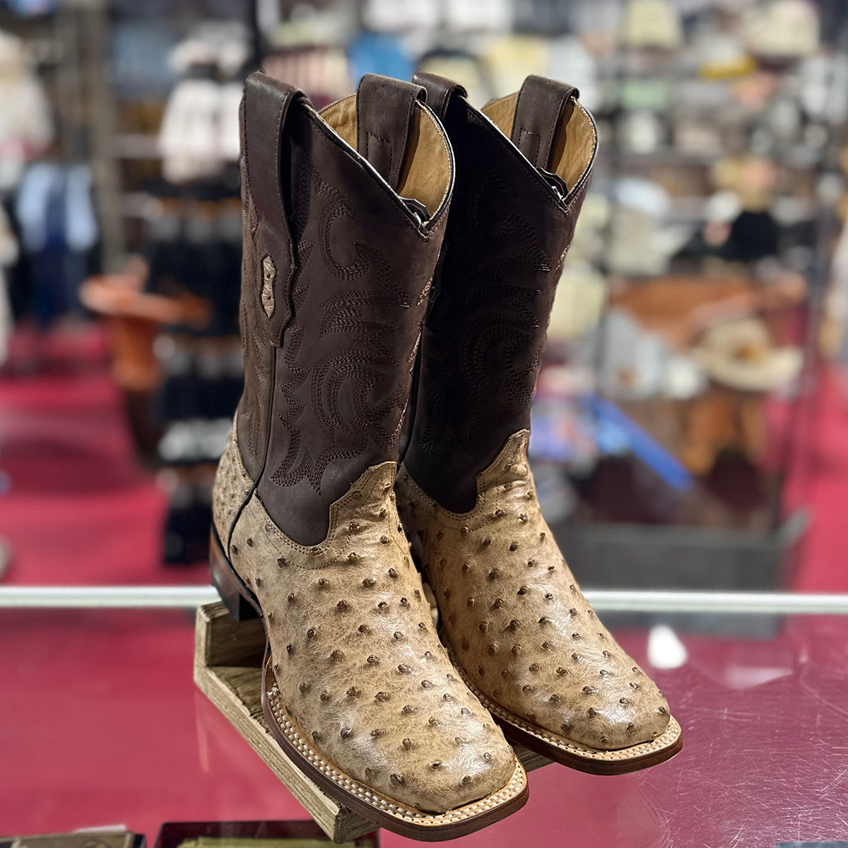 In-store close-up pair view of the Los Altos moka ostrich square toe boots highlighting the double-welt stitched sole and raised quill bumps.