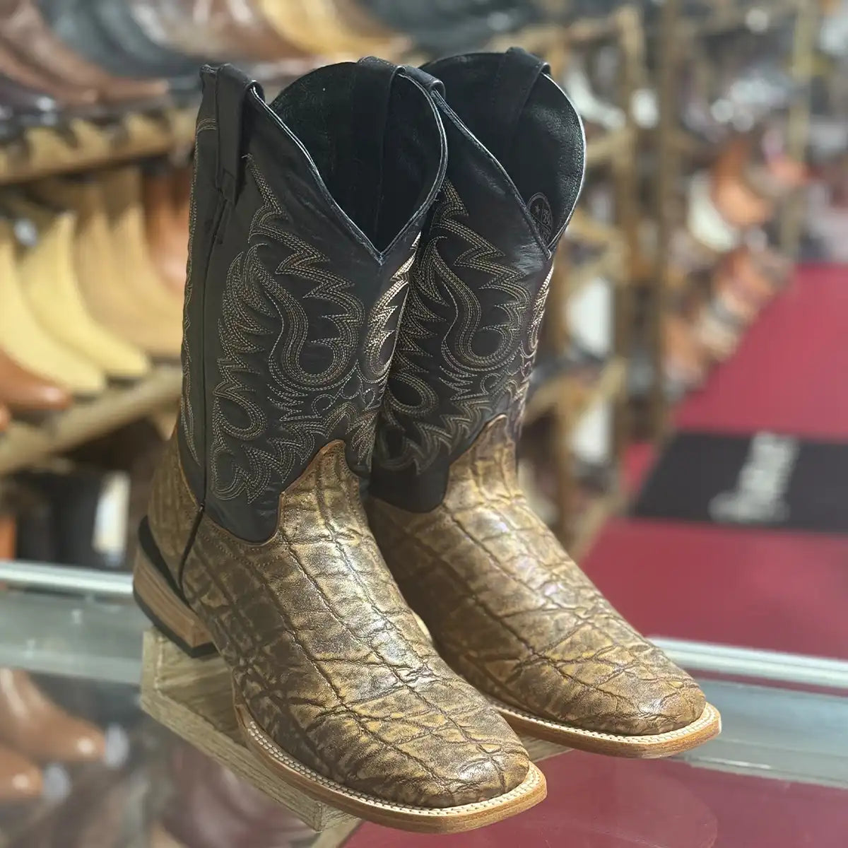 Quincy Men's elephant print leather western boots with wide square toe displayed on a glass shelf.