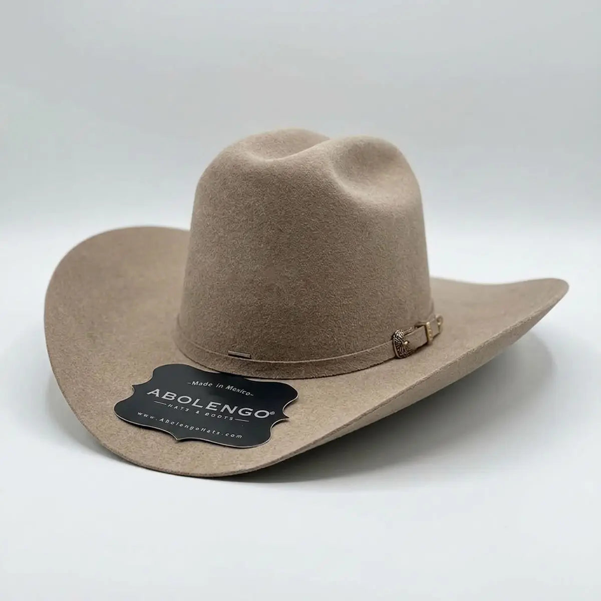 Three-quarter studio view of the Abolengo Rancheron 1000X natural taupe cowboy hat displaying the high Cattleman crown crease and silver buckle detail.