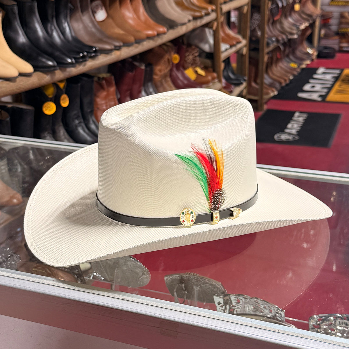 In-store display view of the Abolengo San Judas Tadeo 1000X Chaparral straw cowboy hat resting on a glass counter, highlighting the fine weave, black hatband, and feather.