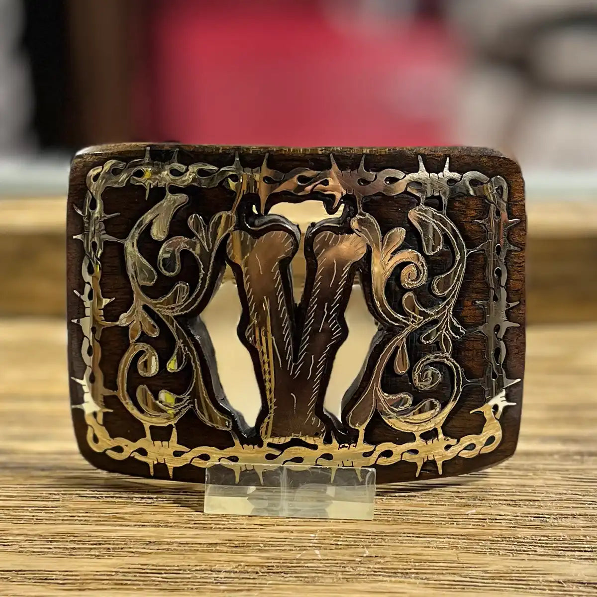 In-store counter display view of the handcrafted mesquite wood belt buckle showing the Monogram V inlay on an acrylic stand.