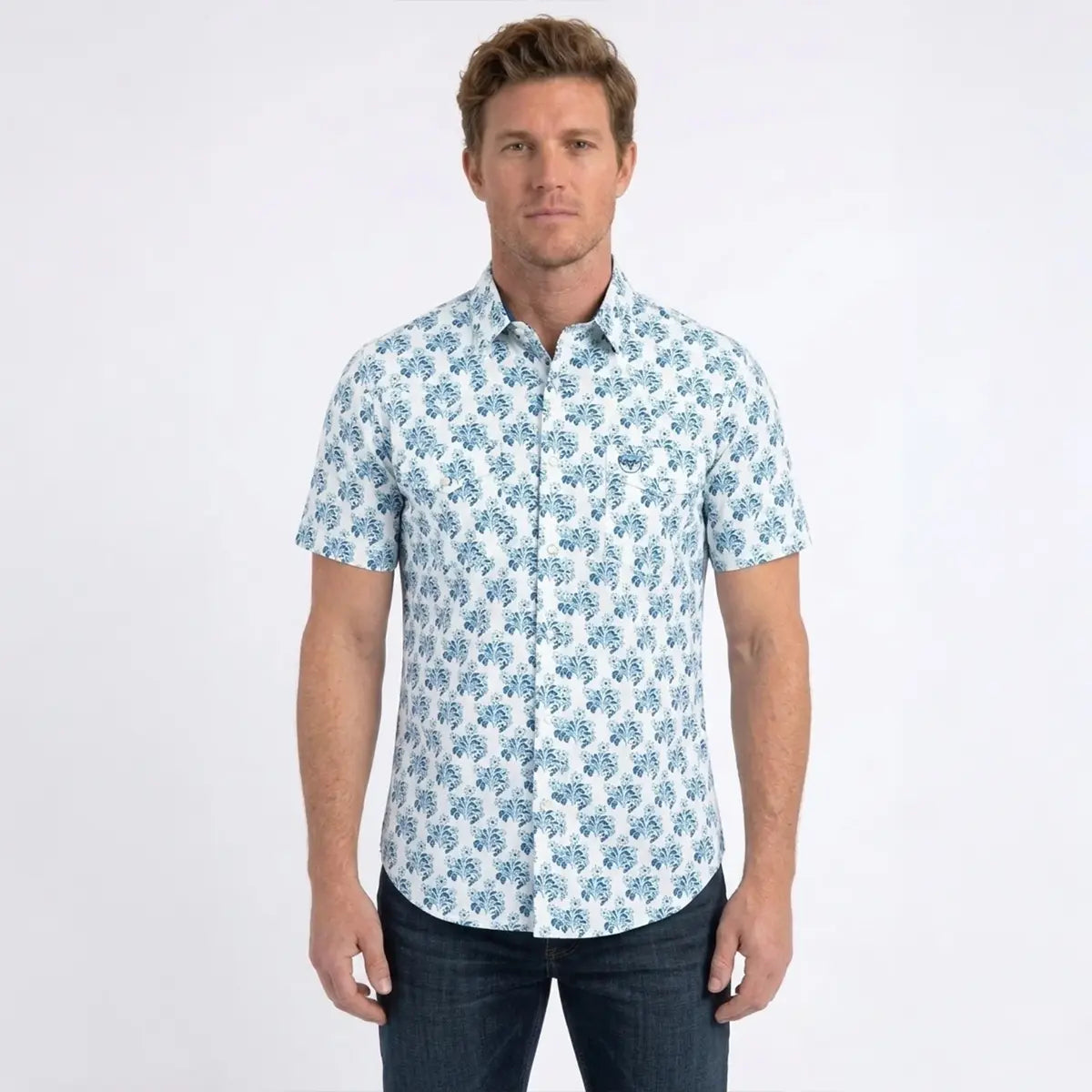 Front studio view of a male model wearing the Platini Men's white and blue floral short sleeve Western snap shirt paired with dark jeans.