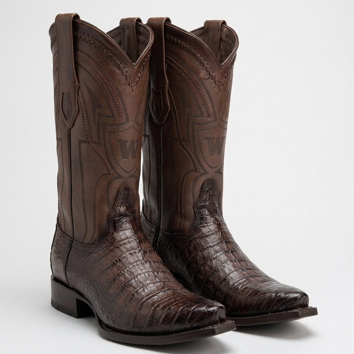 A pair of Wild West men's dark brown western cowboy boots in a genuine caiman belly alligator leather vamp, featuring stitched details and pull loops, shown against a light gray background.