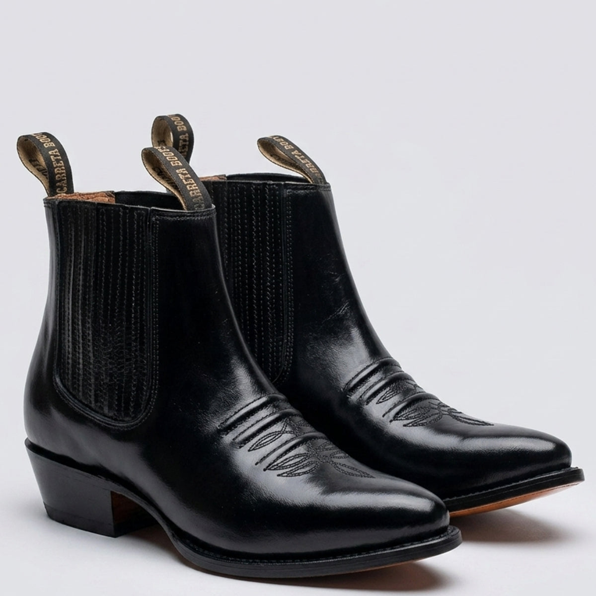 Carreta Boots men's high-shine black leather Western ankle boots featuring elastic side gore panels, pointed toe, and underslung Cuban heel.