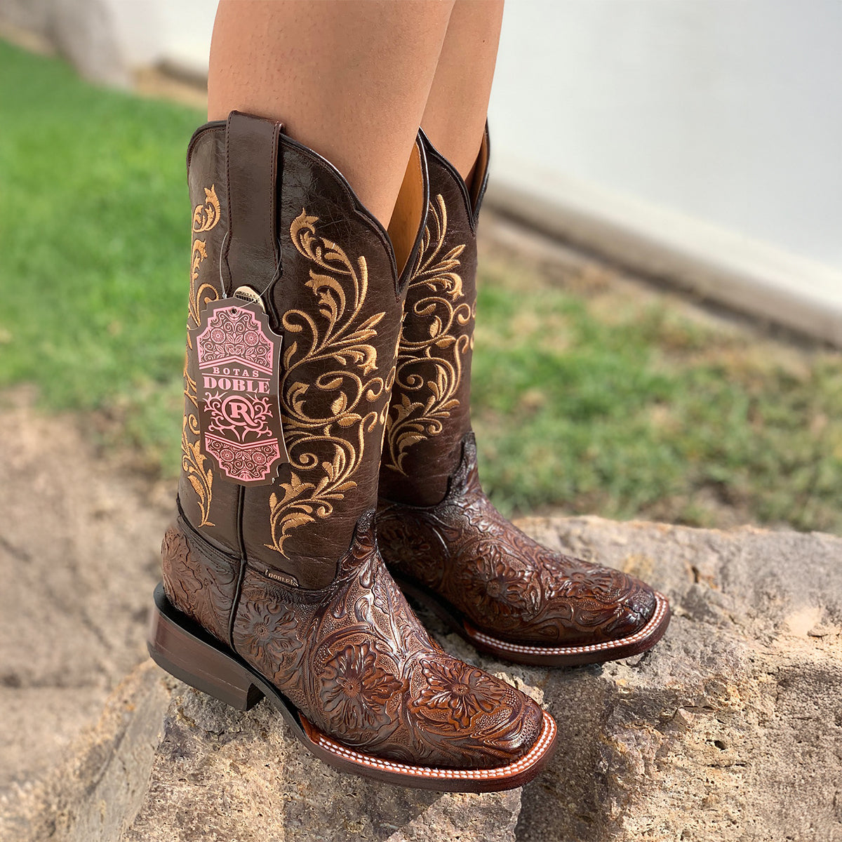 Pair of Botas Doble R women's dark brown leather cowboy boots featuring floral-tooled foot beds, square toes, and golden floral embroidery along the shafts.