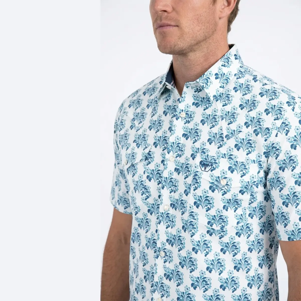 Close-up upper body view of the Platini white floral short sleeve shirt highlighting the collar, pearl snaps, chest pocket logo, and floral detail.