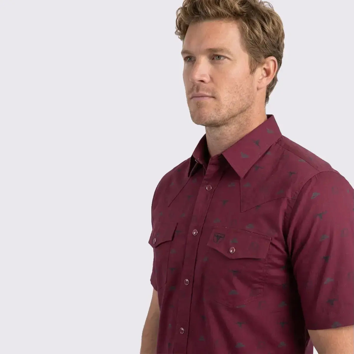 Close-up profile view of the Platini burgundy short sleeve shirt detailing the longhorn and hat icon pattern, Western yoke, and snap pockets.