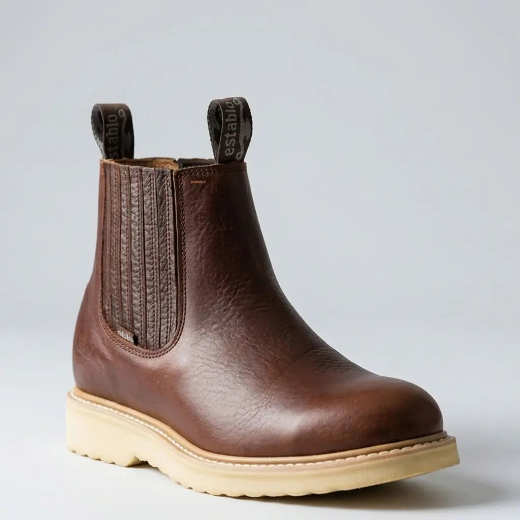 Studio profile view of the Establo Men's honey brown leather pull-on Chelsea work boot showing the elastic side gore, woven pull tabs, and cream wedge sole.