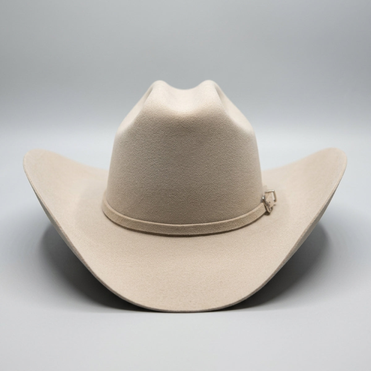 Serratelli light beige felt cowboy hat with a matching band and a small silver buckle, photographed against a neutral gray background.