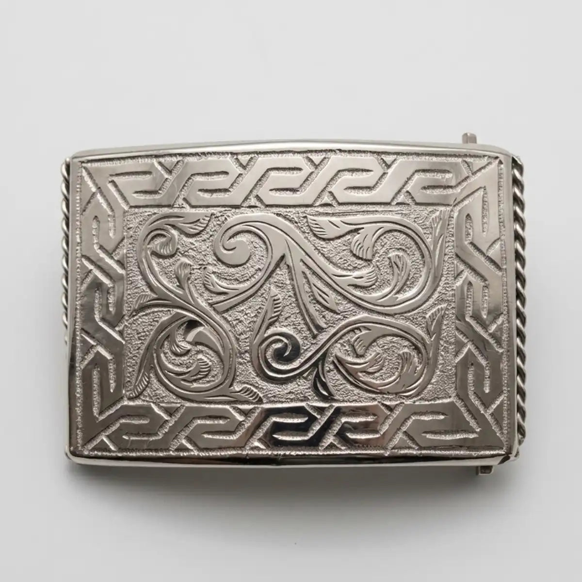 Studio white background product shot of the 3.5" x 2.5" stainless steel rectangular belt buckle showing the floral scrollwork, geometric frame, and side rope edge.