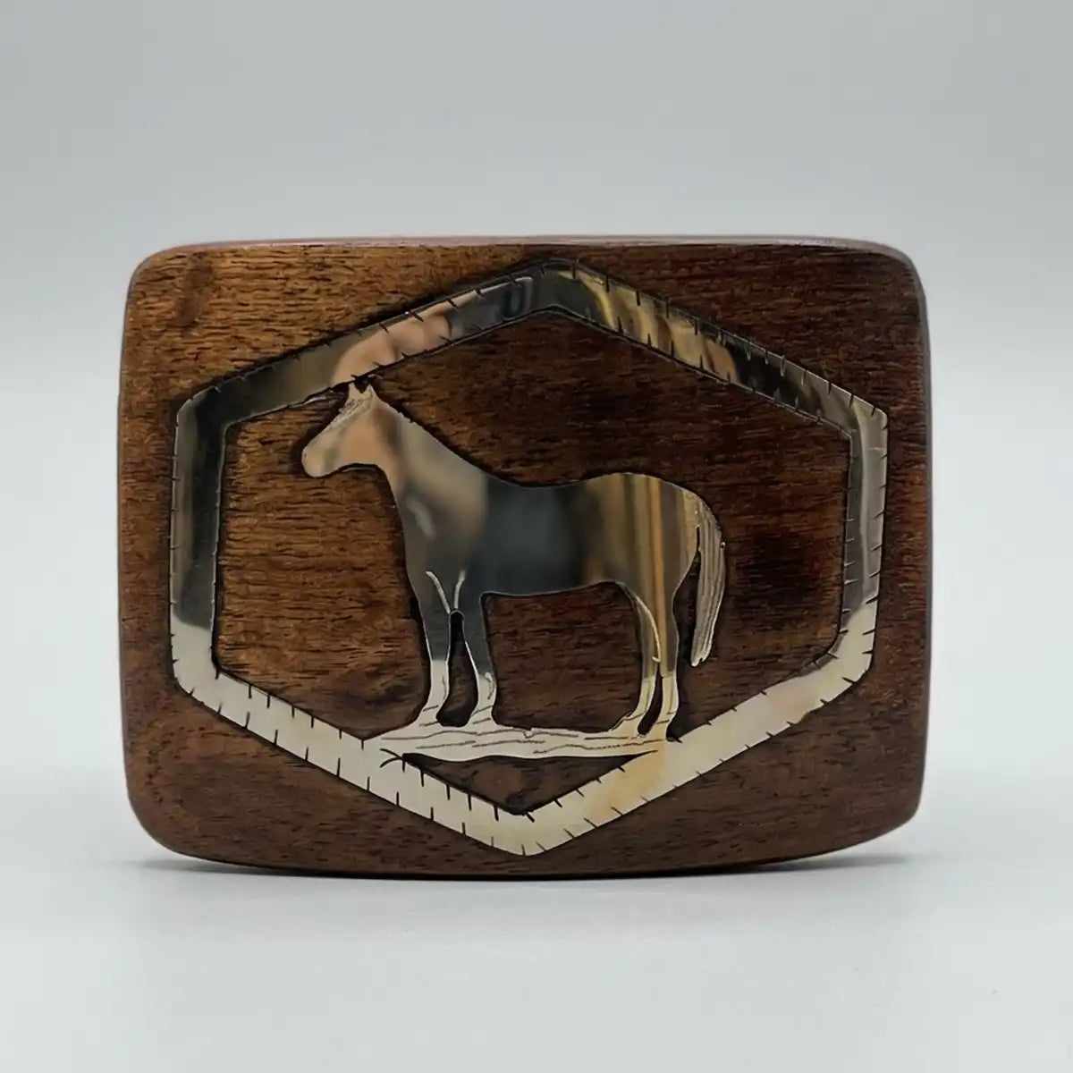Handcrafted mesquite wood vaquero belt buckle with a polished stainless steel horse inlay framed inside a geometric border.