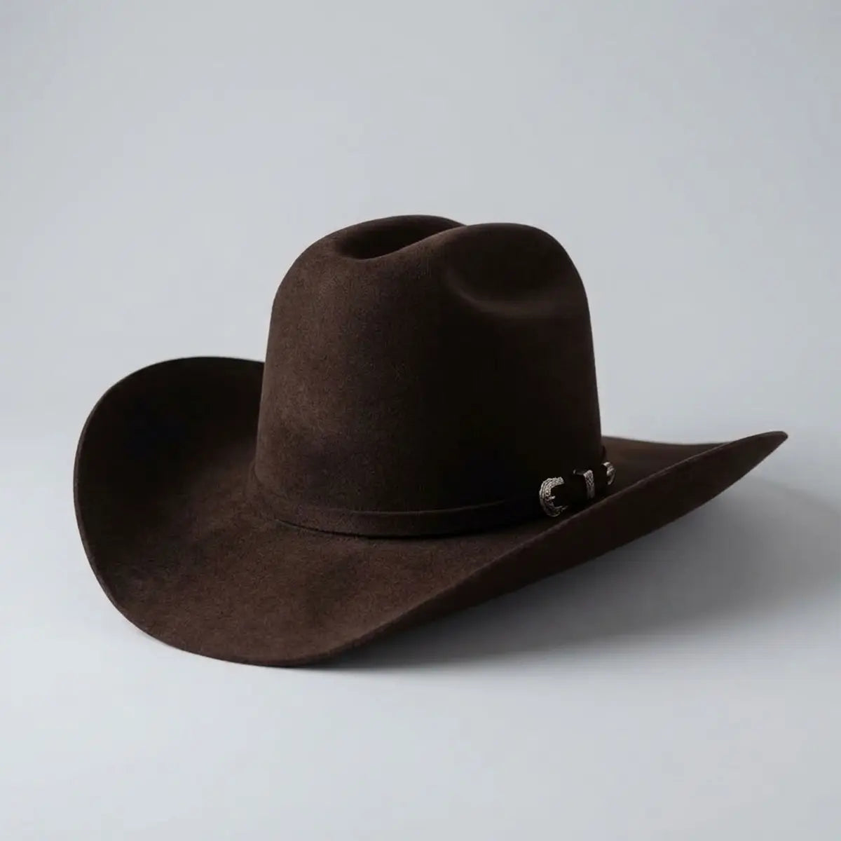 Three-quarter studio profile view of the Abolengo Rancheron 1000X dark brown rabbit fur felt hat displaying the Cattleman crown crease, silver buckle set, and rich felt texture.