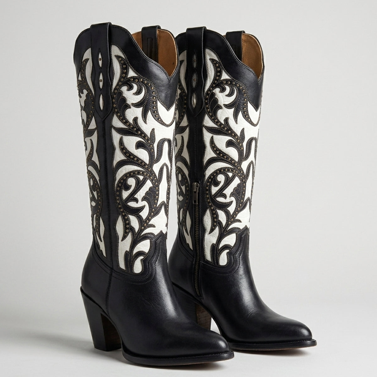 Rio Grande Isabela women's black and white leather cowgirl boots featuring intricate black floral cutouts over white leather, brass studs, and a 3-inch heel.