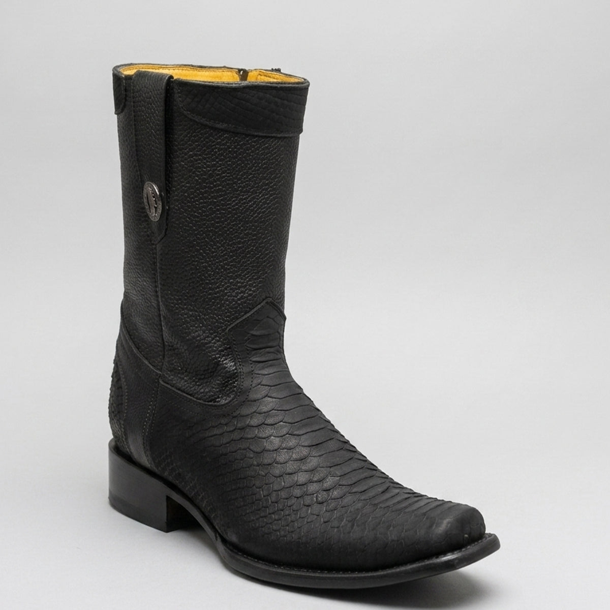 A single black leather cowboy boot with a textured python-patterned shaft and a low block heel, shown on a light gray background.