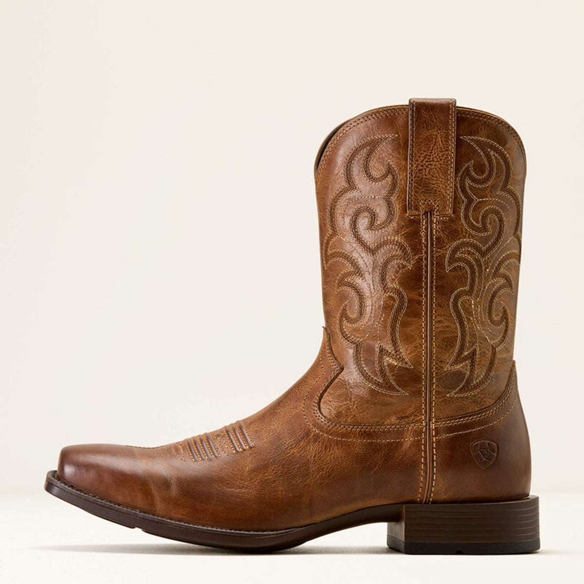 Side profile of men's Ariat Brodie light brown square toe cowboy boot with intricate embossing on a white background.
