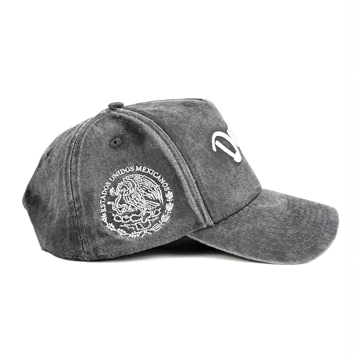 A dark gray acid-wash baseball cap featuring a white embroidered Mexican coat of arms on the side, set against a plain white background.