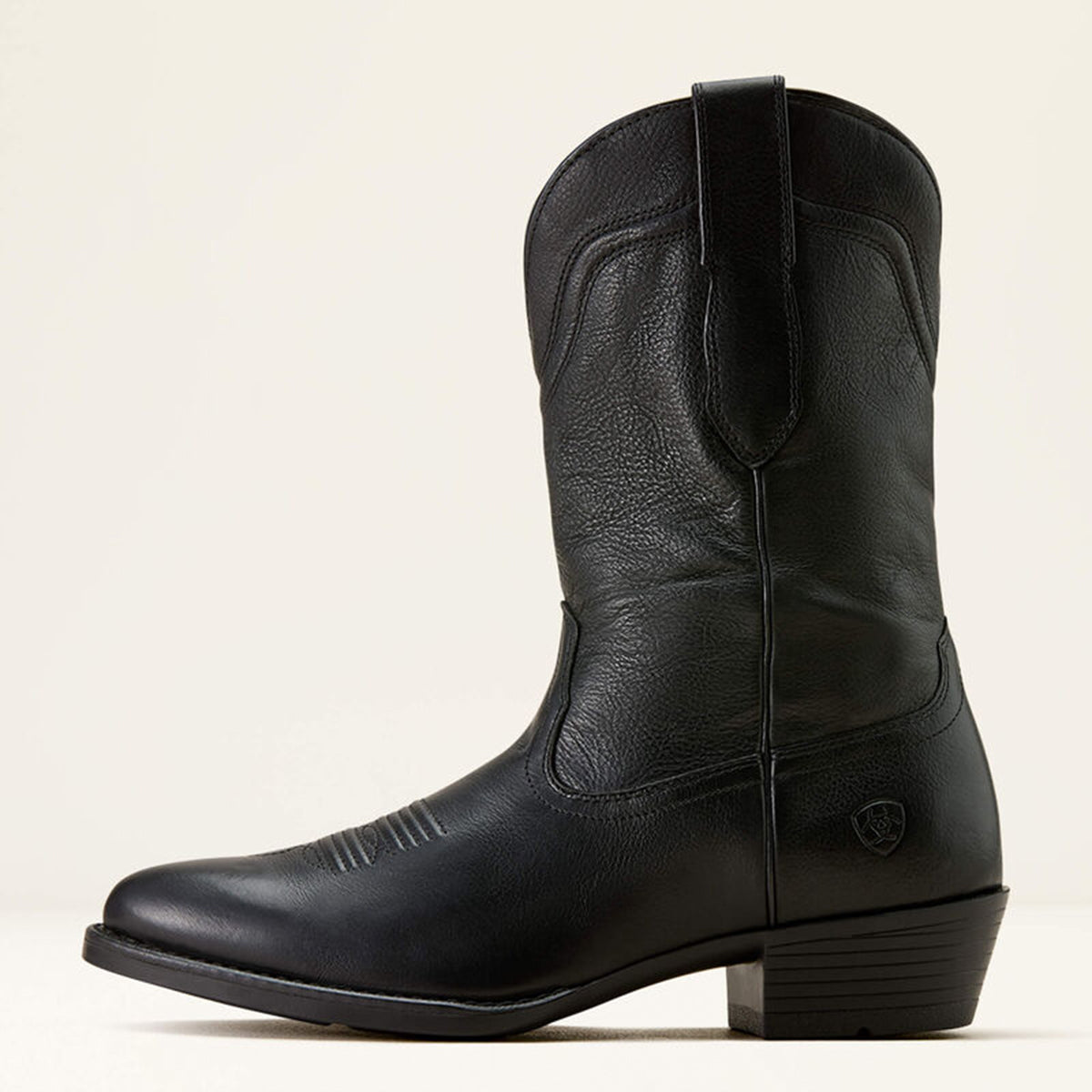 Side view of Ariat men's black leather western boot on a beige background.
