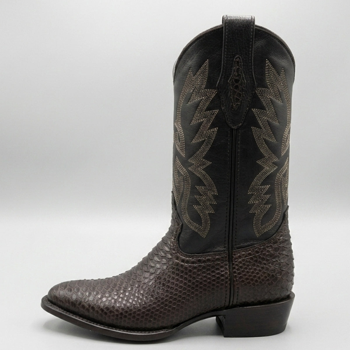 A single dark brown western boot with a textured python-patterned lower section, black shaft, and metallic bronze western embroidery, shown against a light gray background.