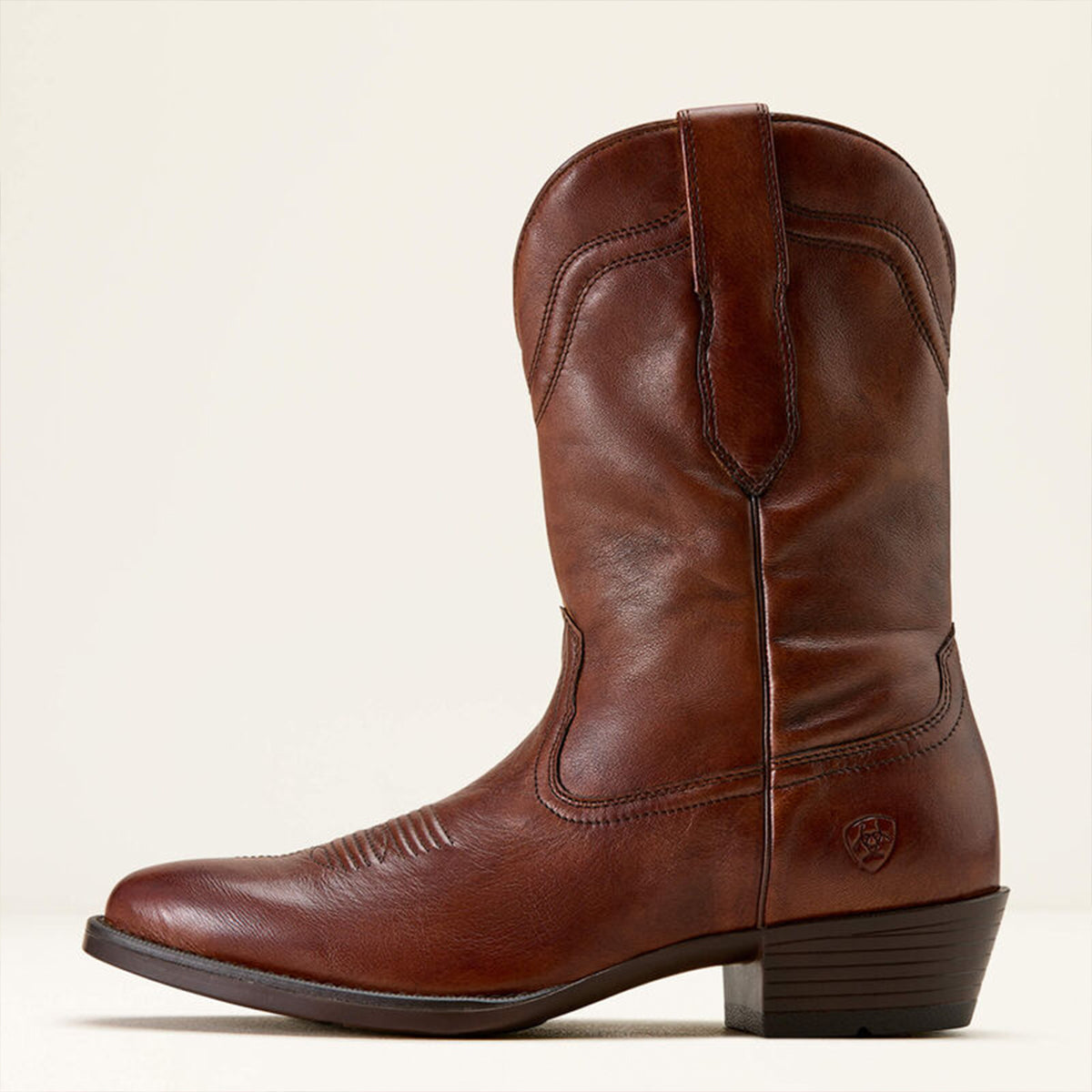 Side profile of Ariat men's brown leather cowboy boot on a beige background.