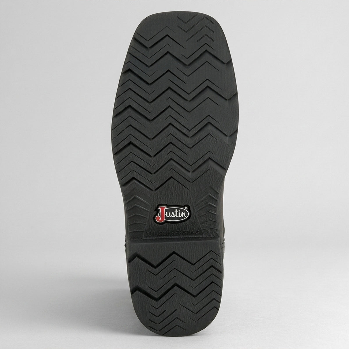 A close-up view of a black shoe sole with a zigzag tread pattern and a small 'Justin' brand logo near the center, set against a light gray background.