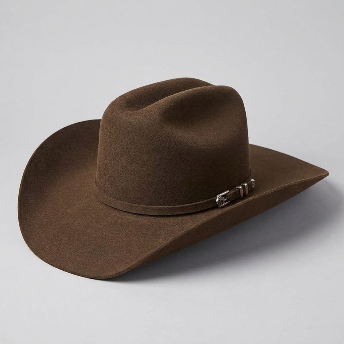 Three-quarter studio profile view of the Stetson Apache 4X mink buffalo felt cowboy hat displaying the Cattleman crown, 4-inch brim, and silver buffalo buckle set.