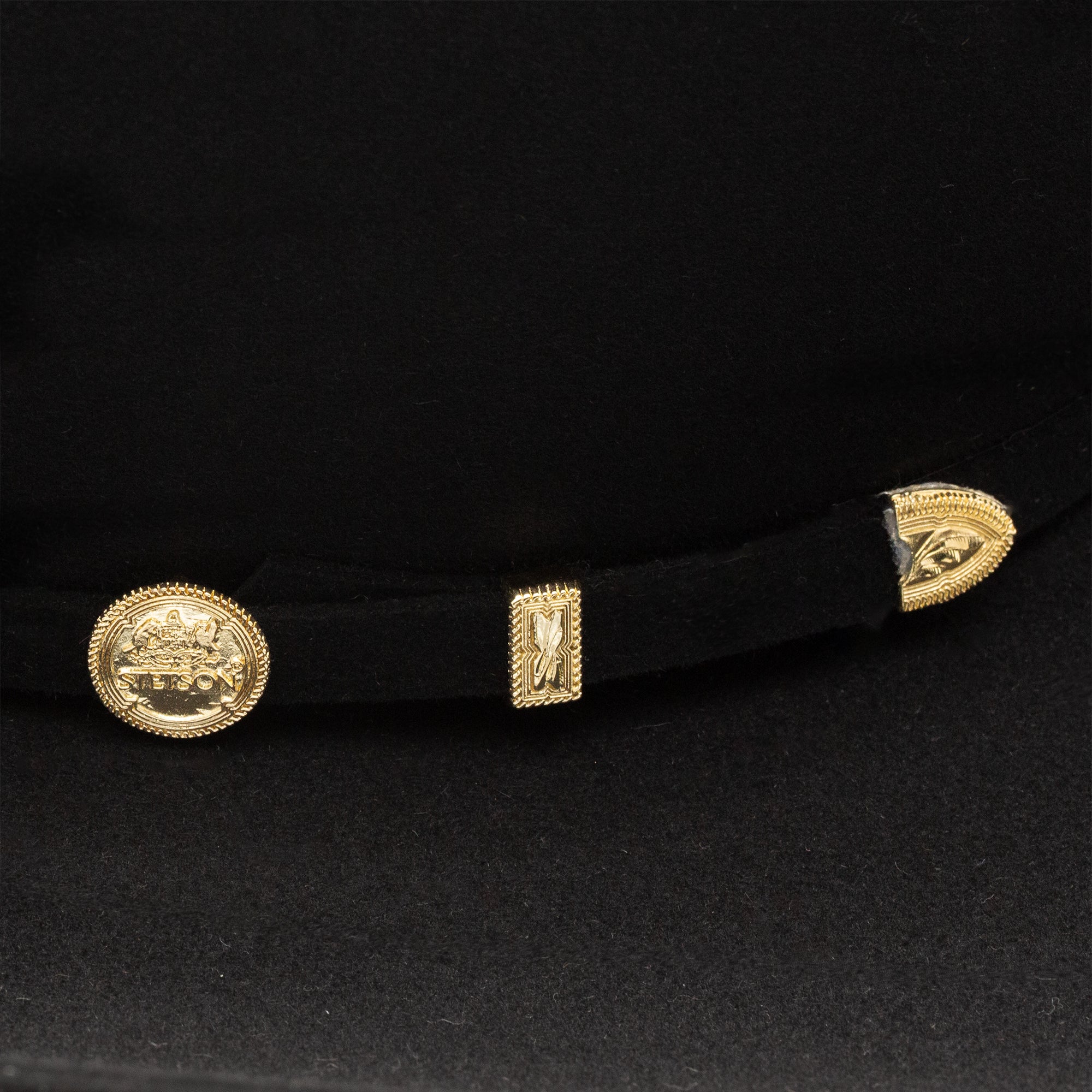 Close-up of a black felt hat with gold buckle.